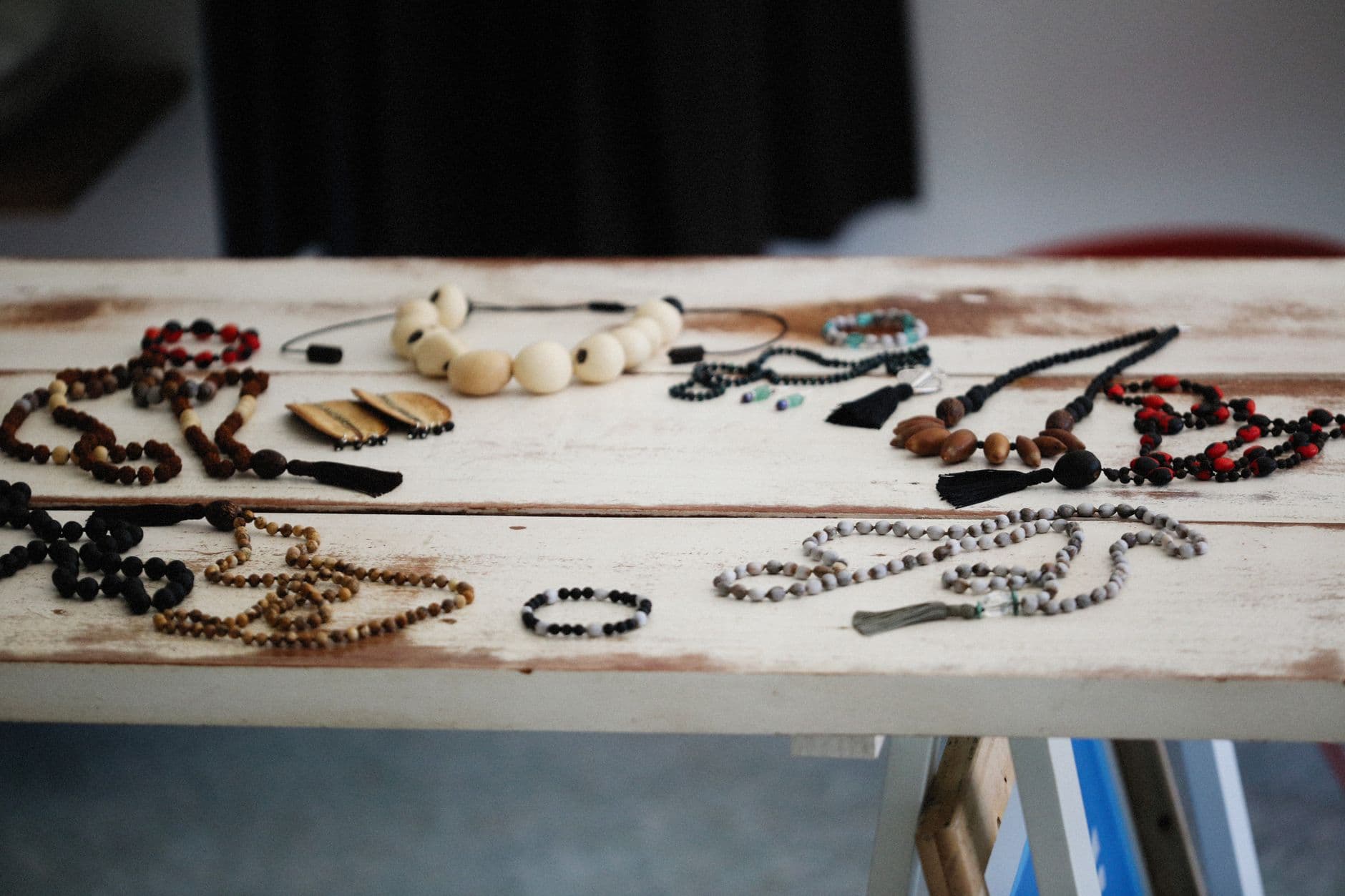 A collection of handmade bohemian necklaces and bracelets arranged on a rustic wooden table.