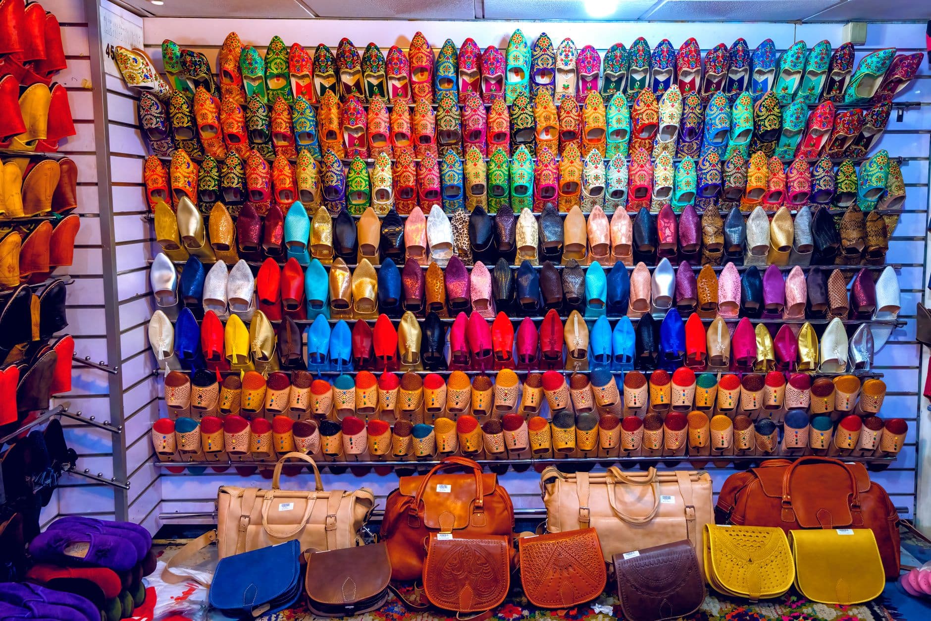 Colorful traditional shoes and leather bags beautifully displayed in an indoor market stall.