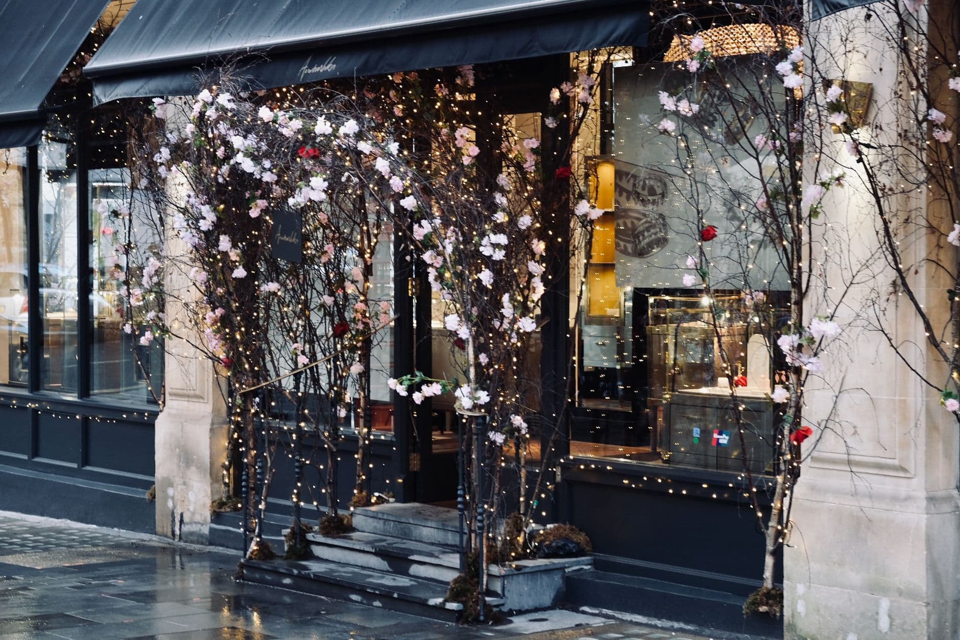 Beautiful shopfront in London adorned with twinkling lights and floral decorations, inviting passersby.