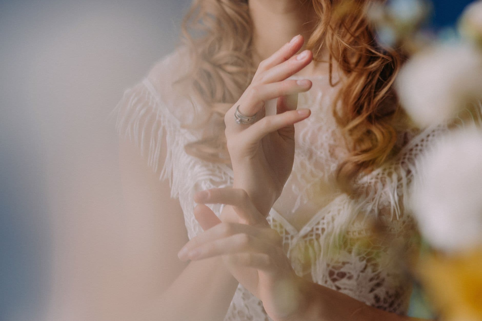 Close-up of a bride's hands adorned with elegant rings and lace, evoking a sense of romantic elegance.