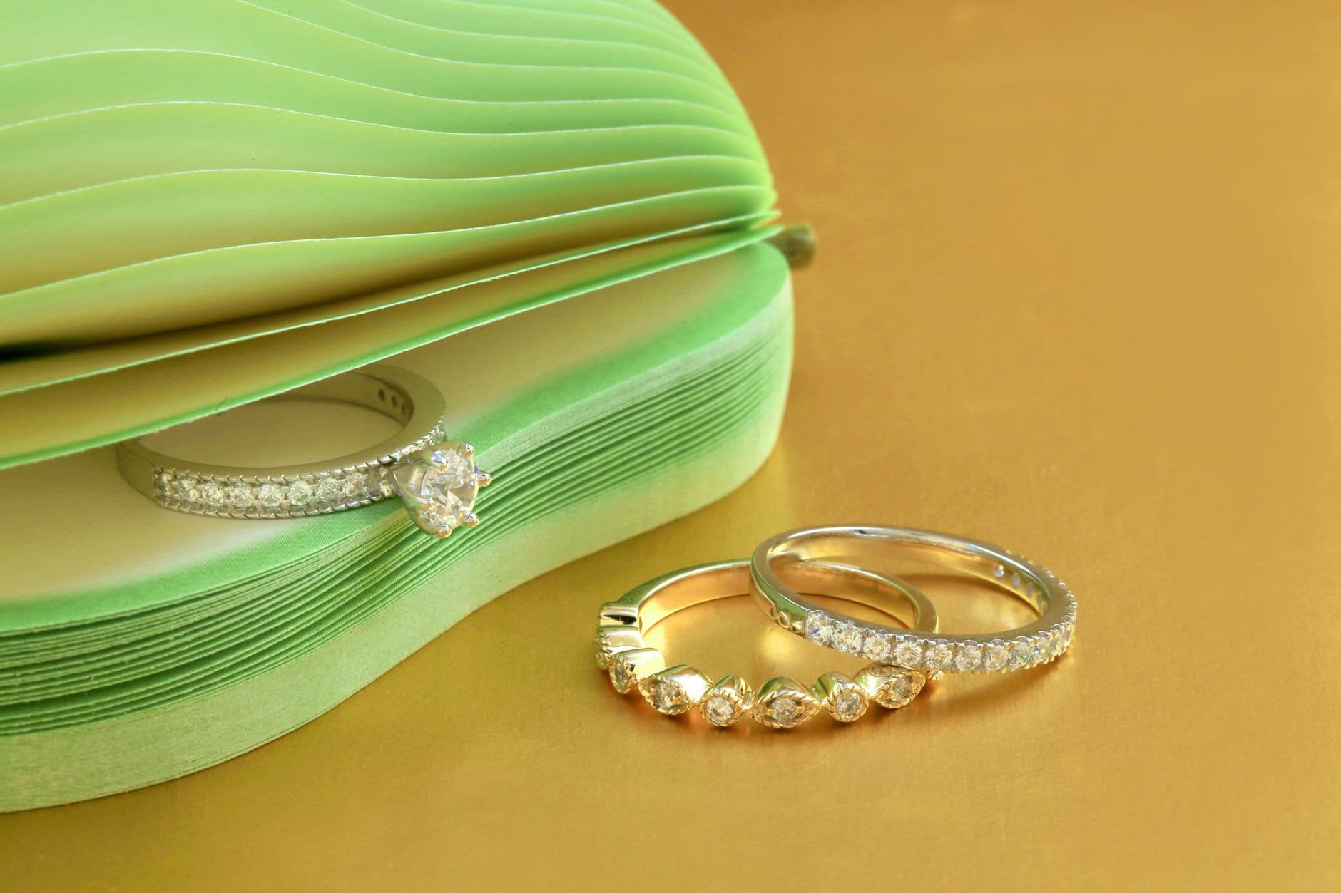 Elegant diamond rings displayed on a gold surface with a chic design.