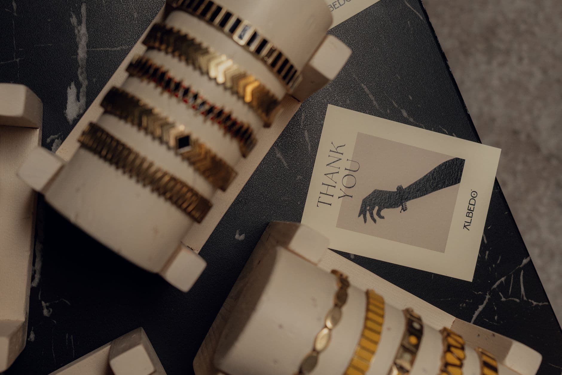 Elegant gold and black bracelets displayed on stands with a thank you card, perfect for fashion and retail themes.