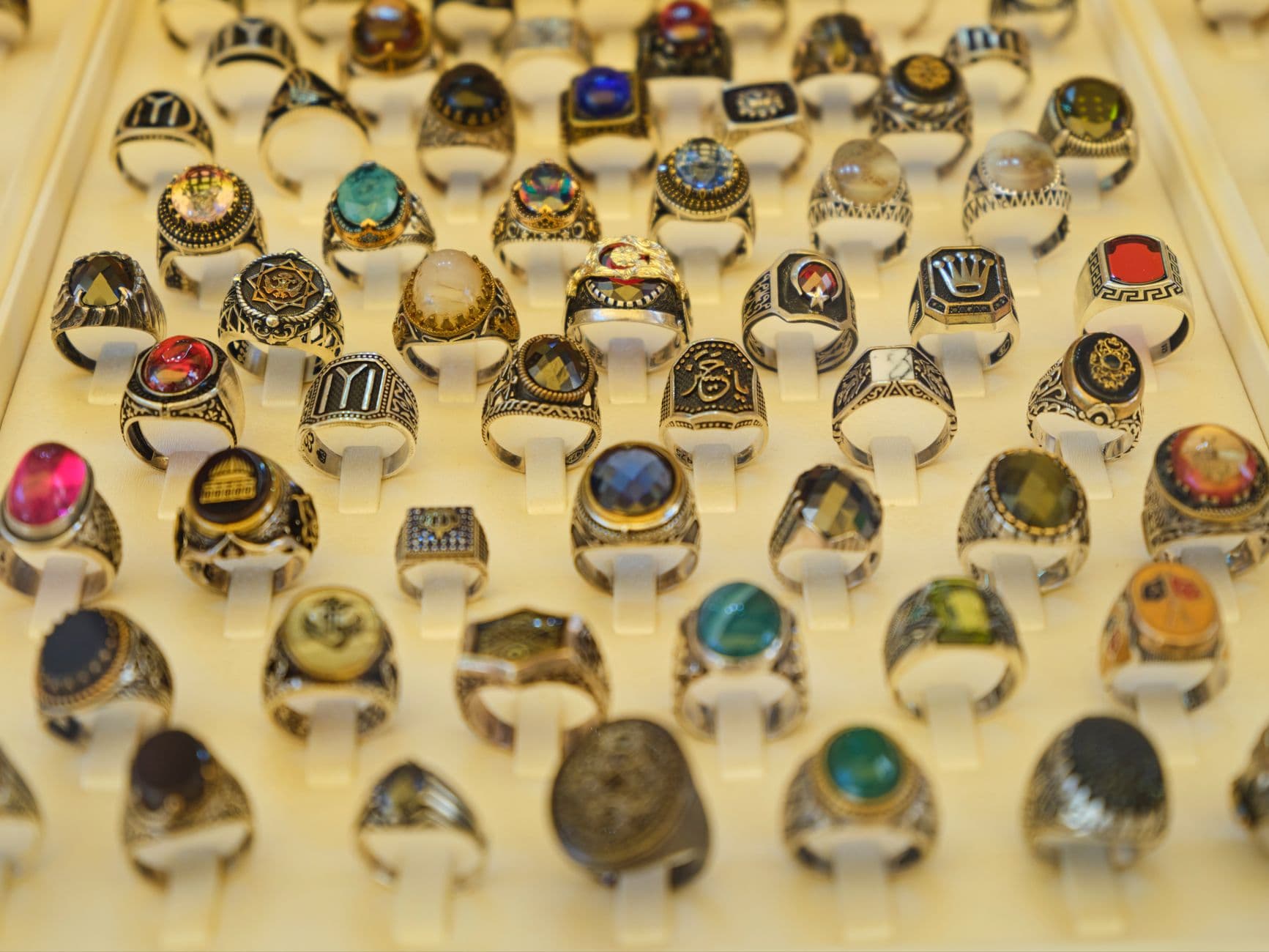 Close-up of assorted gemstone rings in a display case, showcasing intricate design and vibrant colors.