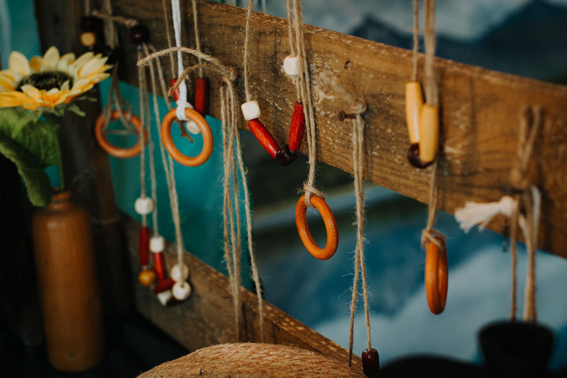 A rustic display of handmade beaded and wooden jewelry hanging outdoors on twine.