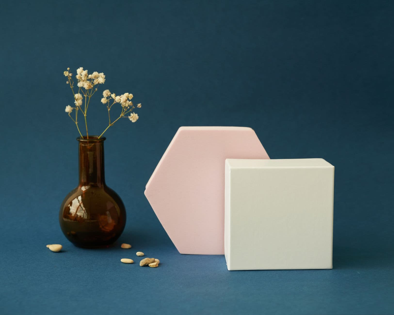 Artistic still life with a vase and geometric shapes against a blue backdrop.