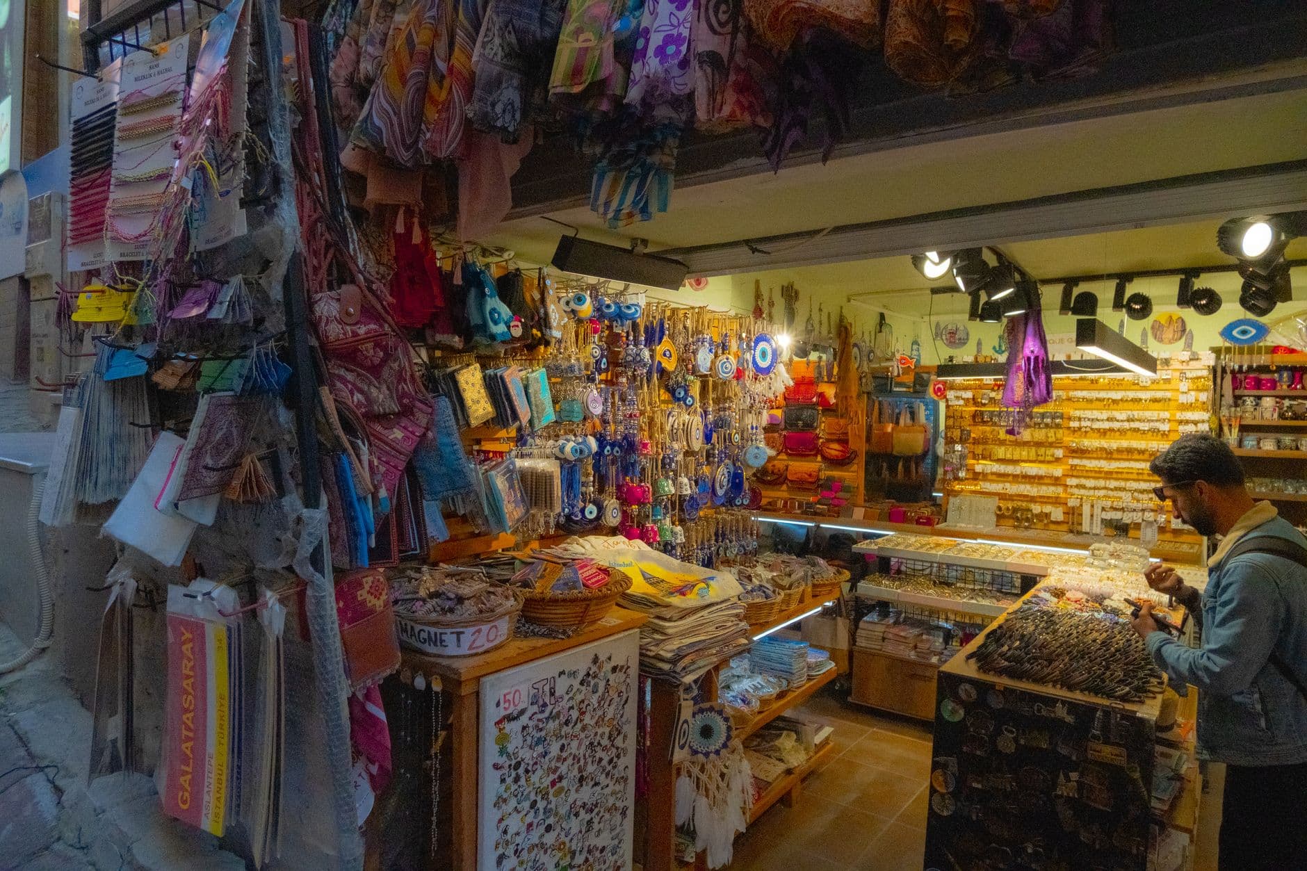 Discover a lively Turkish market stall showcasing diverse traditional crafts and souvenirs, including evil eye charms and textiles.