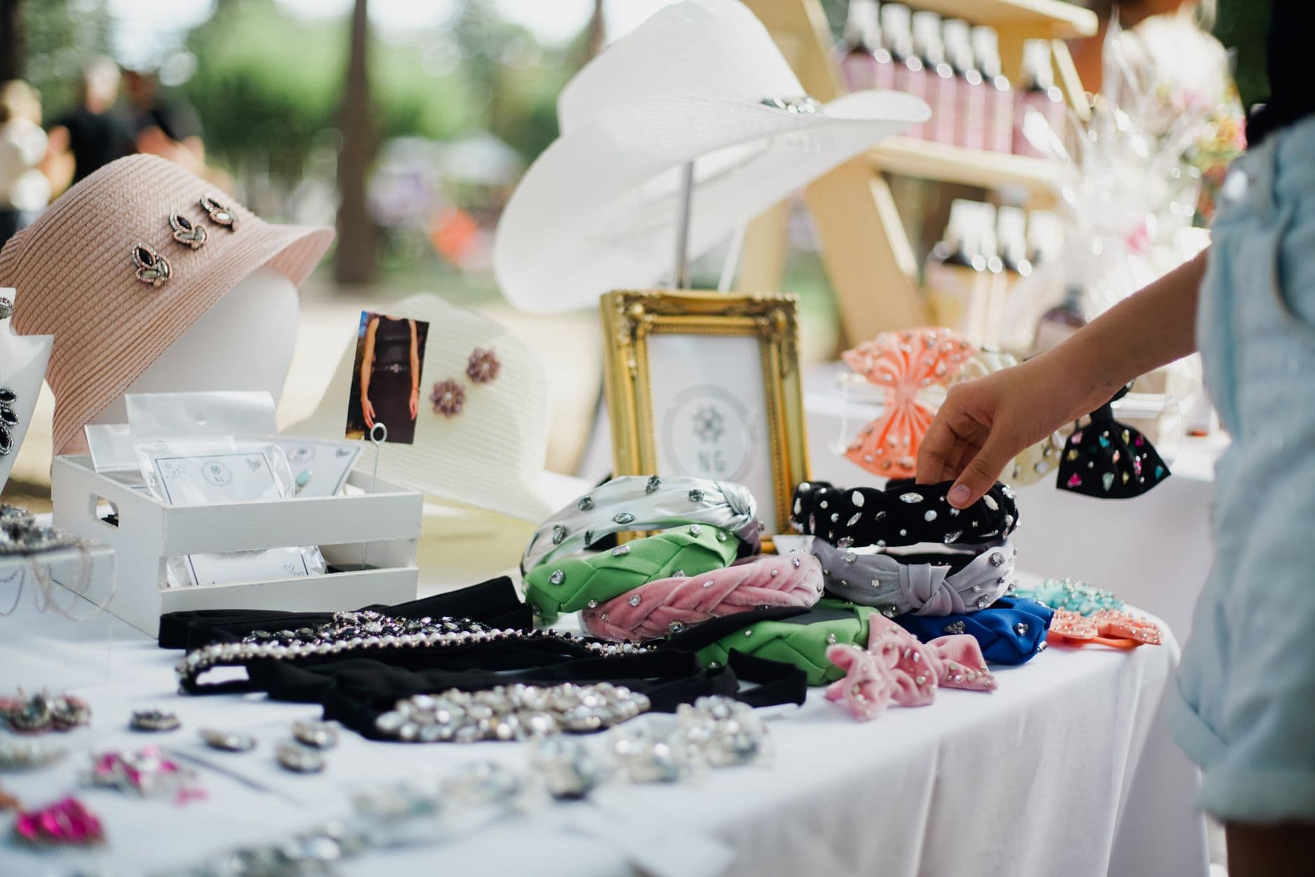 Colorful display of fashion accessories at outdoor market stall featuring hats and headbands.
