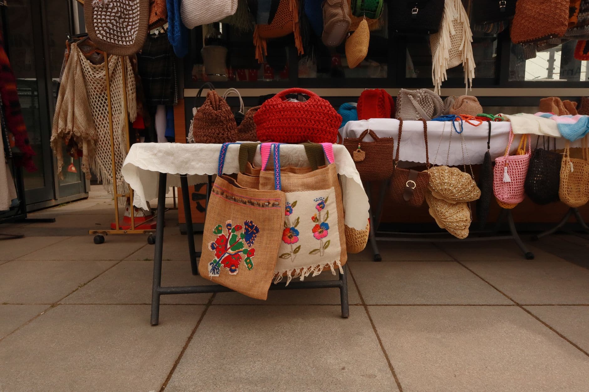 A variety of handcrafted bags showcased on an outdoor market stall, perfect for fashion enthusiasts.