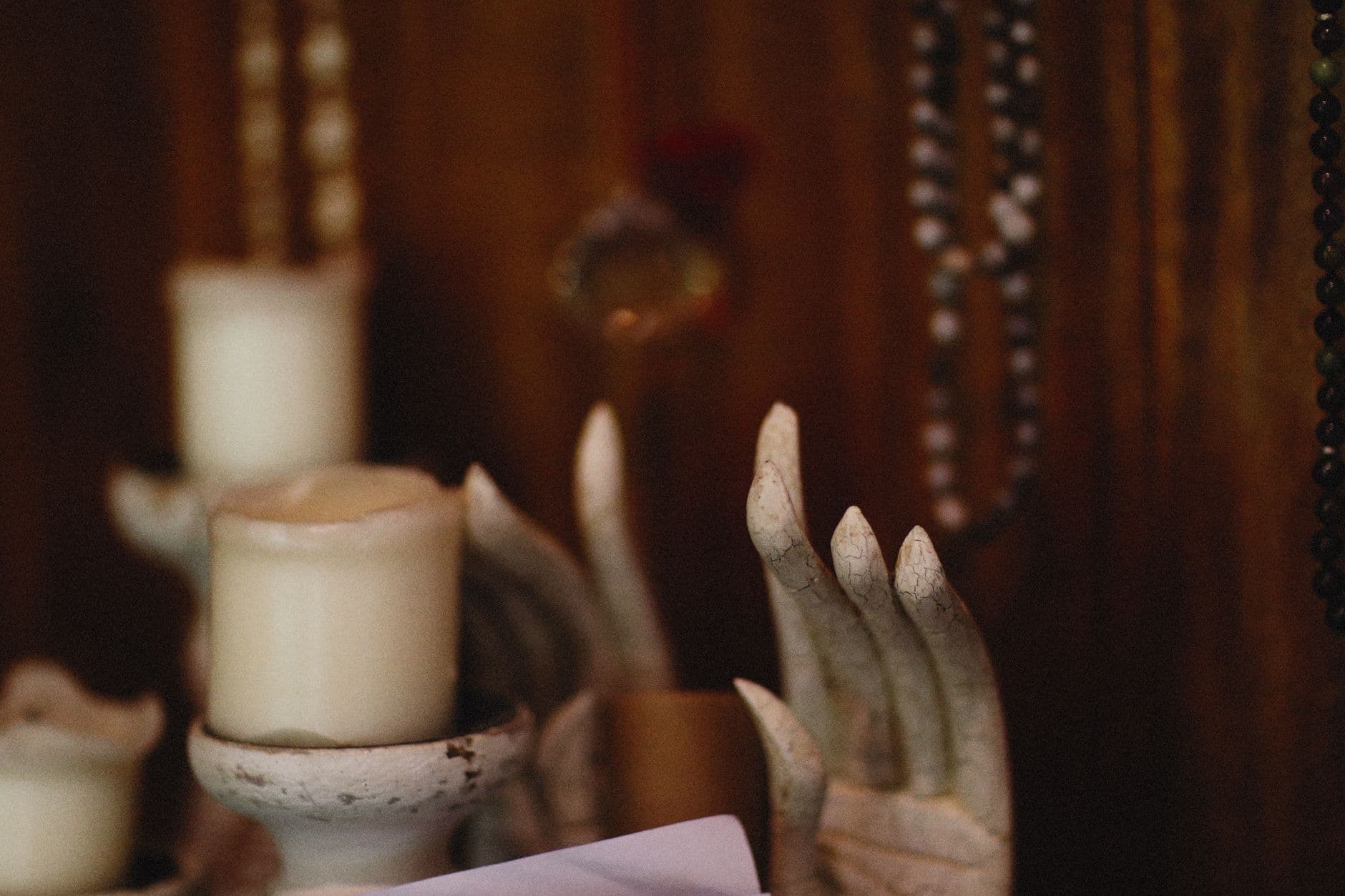 Atmospheric image featuring candles and artistic hand sculptures creating a mysterious ambiance.