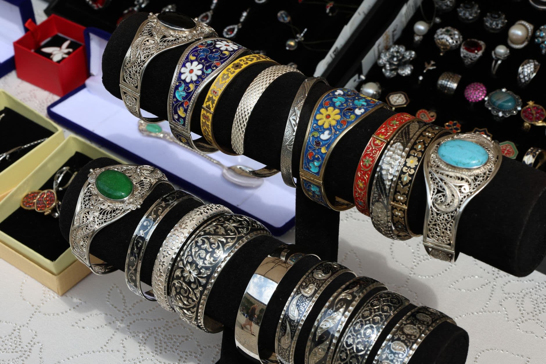 Colorful and intricate silver bracelets on display at a jewelry market stall, showcasing craftsmanship.