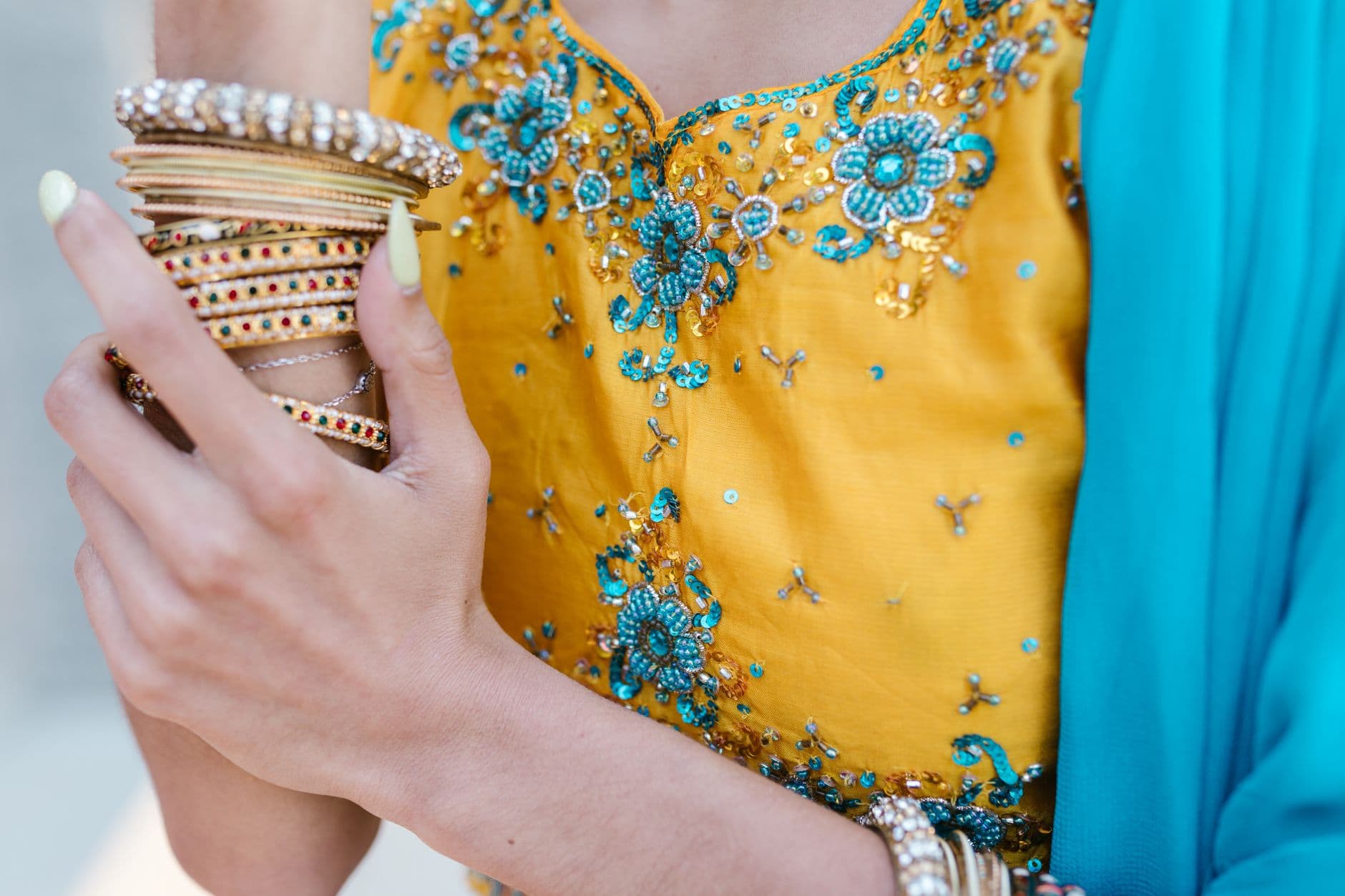 A detailed view of colorful bangles and an embroidered dress, highlighting cultural adornments.
