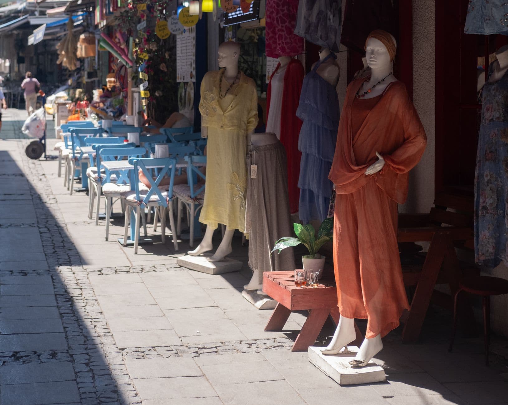 Vibrant display of mannequins in colorful dresses on a sunny street in İzmir, Türkiye.