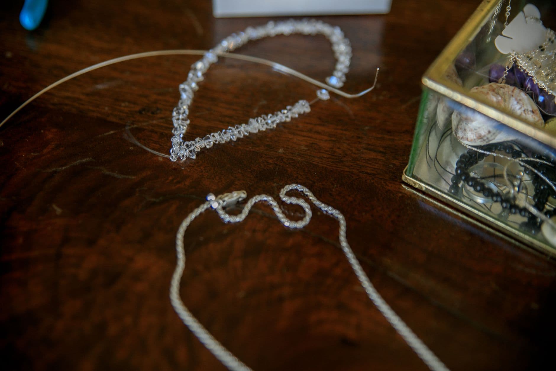 Close-up of elegant silver necklaces on a wooden table with a jewelry box.