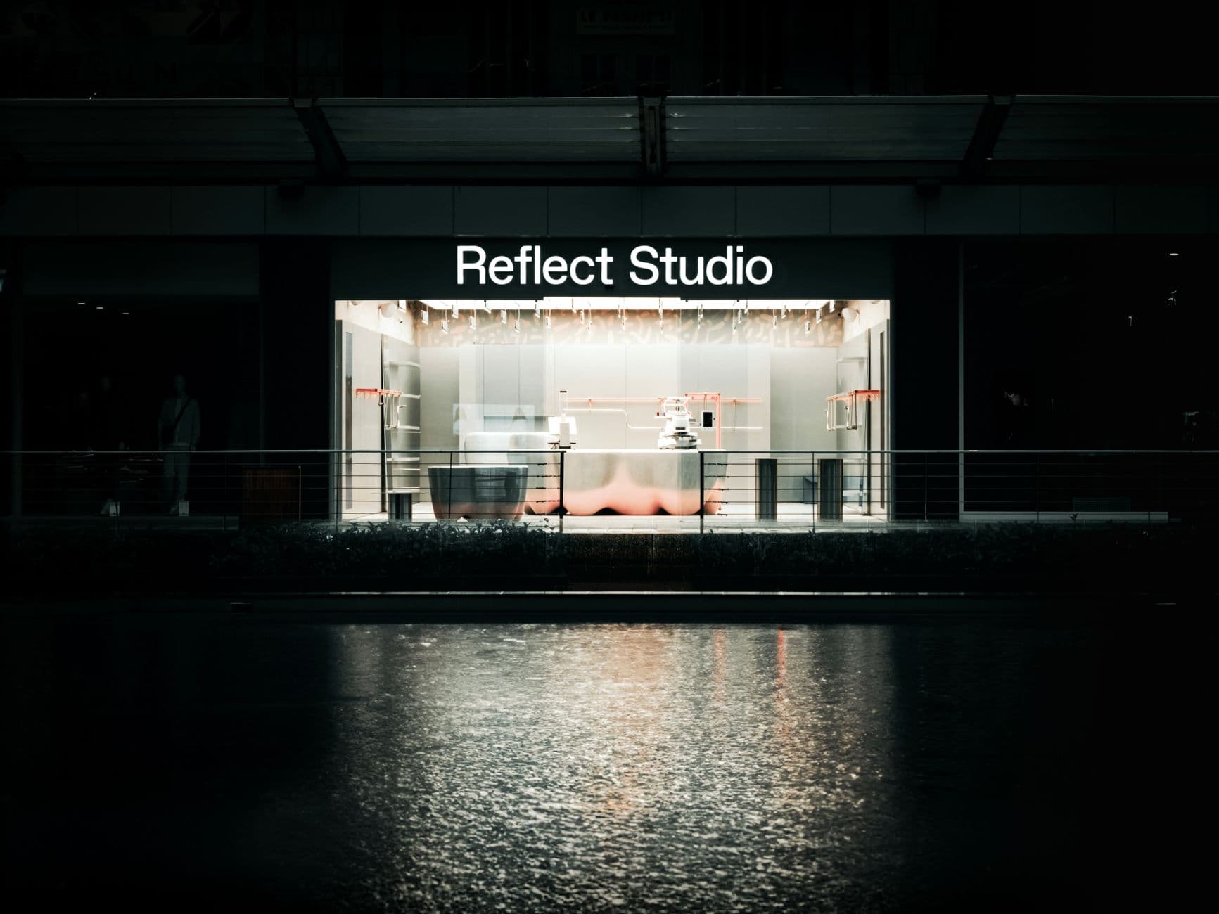 Stylish urban studio exterior in Bursa at night reflecting on water.